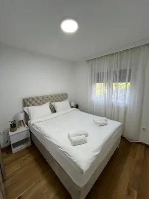 a bedroom with a white bed with two towels on it at Woody apartman in Vrnjačka Banja