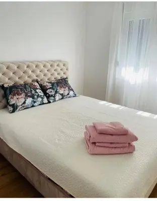 a bed with three folded pink towels on it at Woody apartman in Vrnjačka Banja