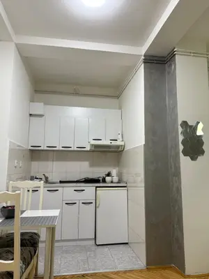 a kitchen with white cabinets and a white refrigerator at Loli apartman in Kraljevo