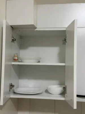 a white cabinet with plates and bowls in it at Loli apartman in Kraljevo