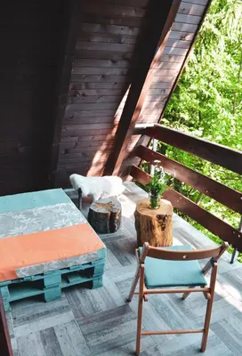 a cat standing on a deck with a table and a chair at Cabin & Apartment Kopaonik in Kopaonik
