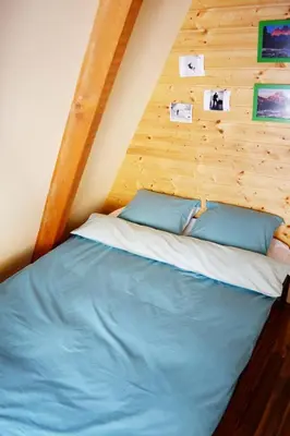 a bed in a room with a wooden wall at Cabin & Apartment Kopaonik in Kopaonik