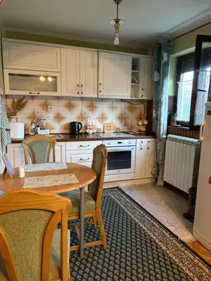 a kitchen with white cabinets and a table with chairs at Apartman 23 in Kraljevo