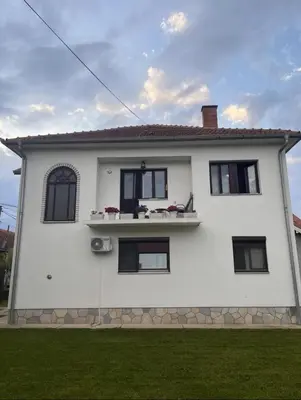 a white house with black windows and green grass at Apartman 23 in Kraljevo