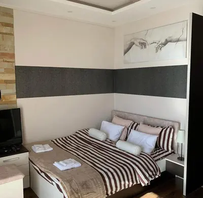a small bedroom with a bed and a television at Milmari I2 Studio LUX Apartman in Kopaonik