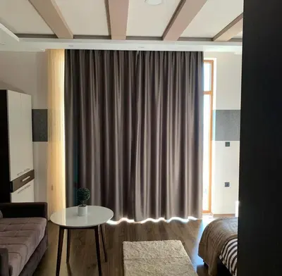 a living room with a couch and a table in front of a window at Milmari I2 Studio LUX Apartman in Kopaonik