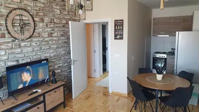 a living room with a table and a brick wall at Apartman Iris in Niš