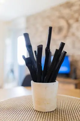 a cup filled with black sticks sitting on a table at Apartman Iris in Niš