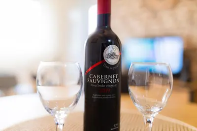 a bottle of wine sitting next to two wine glasses at Apartman Iris in Niš