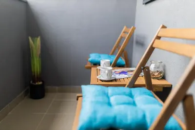 two wooden chairs with blue cushions and a table at Apartman Iris in Niš