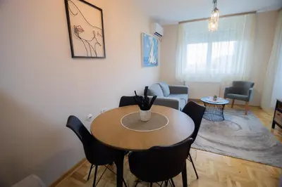 a living room with a table and chairs and a couch at Apartman Iris in Niš
