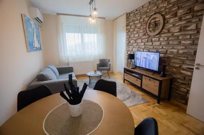 a living room with a table and a tv at Apartman Iris in Niš