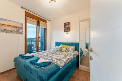 a bedroom with a blue bed and a window at MED Apartmani in Vrnjačka Banja