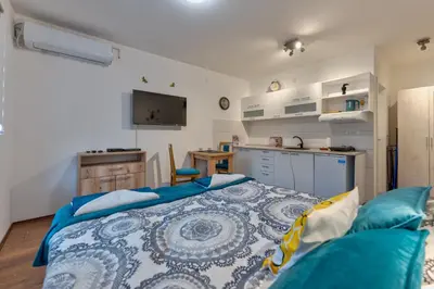 a bedroom with a blue bed and a kitchen at MED Apartmani in Vrnjačka Banja
