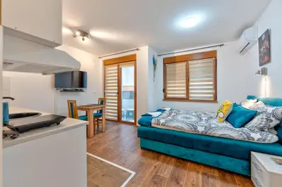 a living room with a blue couch and a kitchen at MED Apartmani in Vrnjačka Banja