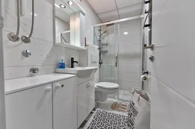 a white bathroom with a shower and a sink and a toilet at MED Apartmani in Vrnjačka Banja