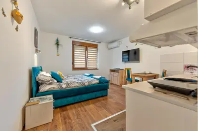 a living room with a blue couch and a kitchen at MED Apartmani in Vrnjačka Banja