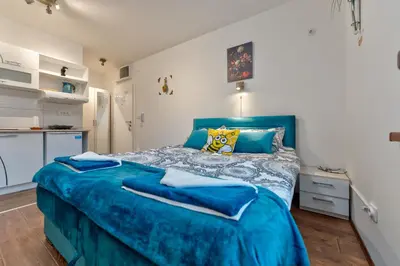 a bedroom with a blue bed and a desk at MED Apartmani in Vrnjačka Banja