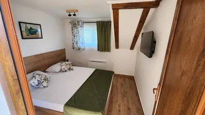 a small bedroom with a bed and a television at Gore Dole in Donji Matejevac