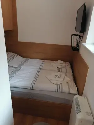 a bed with white sheets and a television on it at Planinski Raj - Bela Reka Gondola in Brzeće