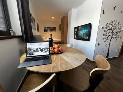 a laptop on a wooden table with a bowl of fruit at ZIMSKI Apartmani in Kopaonik