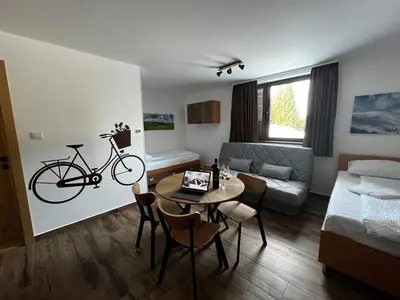 a living room with a table and a bike on the wall at ZIMSKI Apartmani in Kopaonik