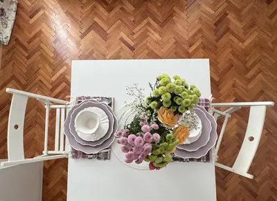 a table with plates and a vase of flowers on it at Vila Lela in Vrnjačka Banja
