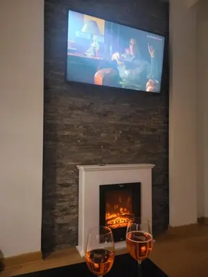 two wine glasses on a table in front of a fireplace at Apartman KUTIJA Kopaonik in Kopaonik