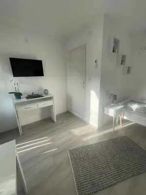 a white living room with a television and a desk at Temački konaci in Pirot