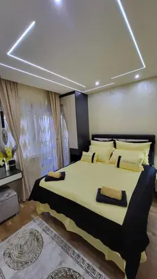 a bedroom with a large bed with yellow pillows at Apartman POSEJDON DELUXE 2 in Vrnjačka Banja