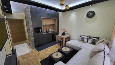 a living room with a white couch and a kitchen at Apartman POSEJDON DELUXE 2 in Vrnjačka Banja