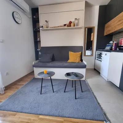 a living room with a blue couch and two tables at studio-apartman ,,ISSA,, in Vrnjačka Banja