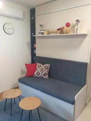 a couch in a room with two tables and a clock at studio-apartman ,,ISSA,, in Vrnjačka Banja