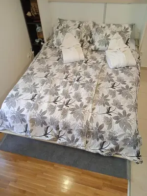 a bed with a gray and white comforter and pillows at studio-apartman ,,ISSA,, in Vrnjačka Banja