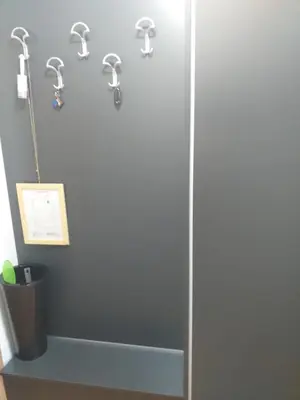 a shower stall with hooks on a wall at studio-apartman ,,ISSA,, in Vrnjačka Banja