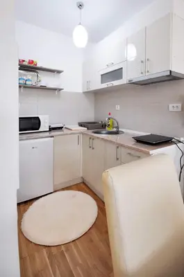 a kitchen with white cabinets and a white rug at Apartman Filipović Vrnjačka Banja in Vrnjačka Banja