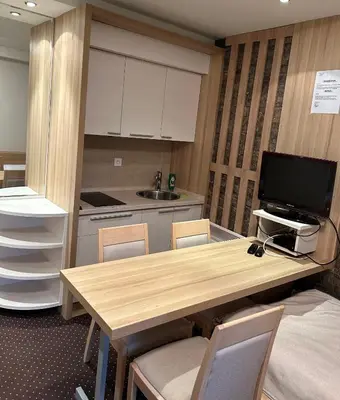 a kitchen with a wooden table with chairs and a television at Apartmani Haski Konaci in Kopaonik
