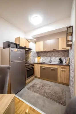 a kitchen with wooden cabinets and a stainless steel refrigerator at Lux Apartmani Rakić in Pirot