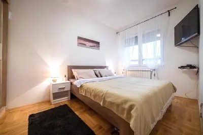 a bedroom with a large bed and a television at Lux Apartmani Rakić in Pirot