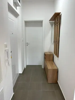 a hallway with a white door and a wooden bench at House Inn 2 in Pirot