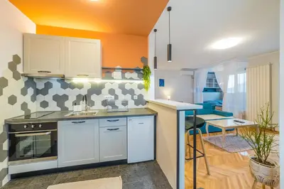 a kitchen with white cabinets and an orange wall at Apartman Nika in Pirot