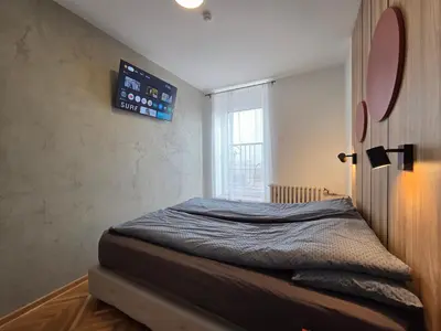a bed in a room with a clock on the wall at Apartman Nika in Pirot