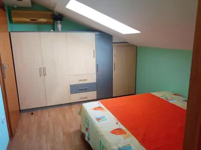 a bedroom with a bed with an orange blanket at Apartman Babić in Vrnjačka Banja