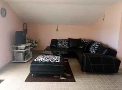 a living room with a black leather couch and ottoman at Apartman Babić in Vrnjačka Banja
