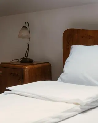 a bed with white sheets and a lamp on a table at Eko Zaseok Brana in Rekovac