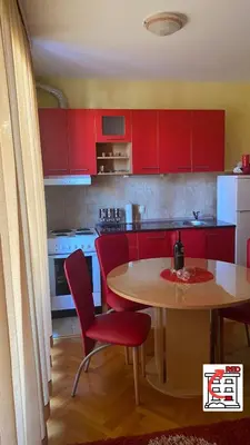 a kitchen with red cabinets and a table and chairs at Apartman RED u Vrnjačkoj Banji in Vrnjačka Banja