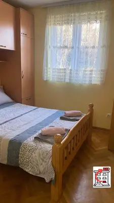 a bedroom with a wooden bed with a window at Apartman RED u Vrnjačkoj Banji in Vrnjačka Banja