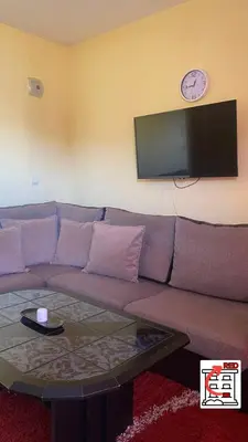 a living room with a couch and a clock on the wall at Apartman RED u Vrnjačkoj Banji in Vrnjačka Banja