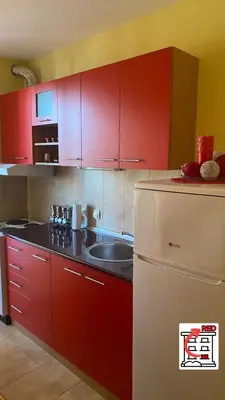 a kitchen with red cabinets and a sink and a refrigerator at Apartman RED u Vrnjačkoj Banji in Vrnjačka Banja