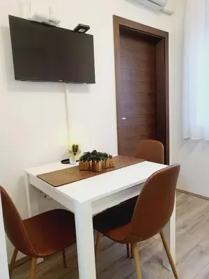 a white dining room table with chairs and a tv at Apartman N Jagodina in Jagodina